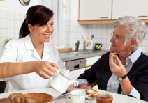 caregiver serving a meal to an old woman